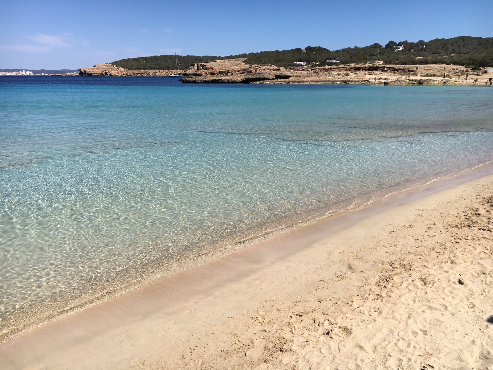 Turquoise shallows and golden sand at a rocky cala, Ibiza