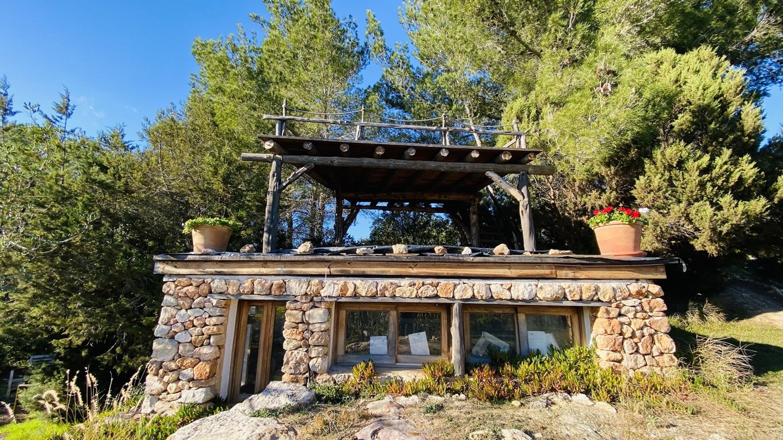 Stone-and-timber cabin with rooftop pergola deck in the pines, Ibiza